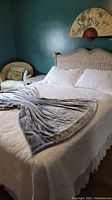 Queen bed made with white quilt and two white pillow shams. Gray plush throw draped over foot of bed. Shows overall bedding set condition and style.