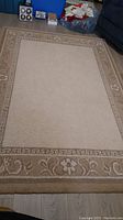 Photo showing the entire 5x7 beige rug with a detailed floral and geometric border.