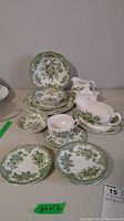 Photo showing full set of plates, bowls, cups, and serving pieces with green floral Wedgwood pattern on white porcelain.