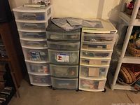 Three shelving storage totes with translucent drawers containing assorted craft supplies