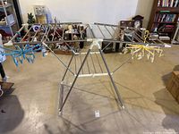 Full view of the folding clothes drying rack setup with clip hanger attachments at the ends.