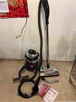 Full view of vacuum unit on castors with hose and wand attached