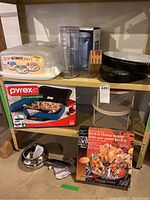 Photo showing cupcake travel case, Brita water pitcher box, cutting tool block, Pyrex portable dish box with case, BBQ chicken roaster box, and stainless steel pan with black handle on shelf