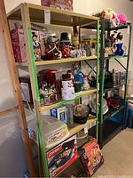 Two metal shelving units side by side with various items stored on the shelves. Grey metal shelf on the right and yellowish shelf on the left.