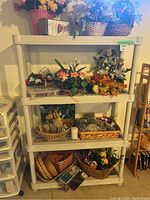 Front view of light colored plastic collapsible shelf with four shelves filled with artificial flowers and baskets
