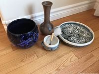 Photo showing all four pottery items grouped on wooden floor: BMP pottery serving plate, matching bowl with spreader, West German planter, and brown vase.