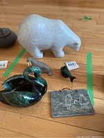 Full group of items on floor including soapstone walrus, polar bear, Blue Mountain Pottery swan, and etched plaque