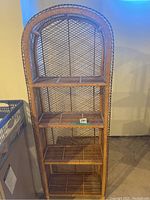 Front view of wicker stand showing four shelves and arched top