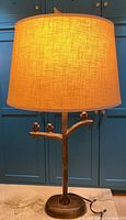 Full view of lamp with shade, base, and cord on marble surface against cabinetry