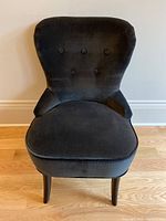 Front view of grey upholstered chair showing button tufted backrest and plush seat cushion.