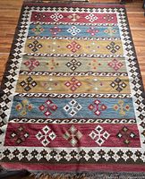 Full view of the Kilim rug showing geometric patterns in multiple colors and border detail.