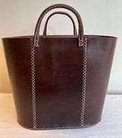 Front view of dark brown leather tote bag showing white cross stitches and rounded bottom edges.