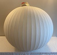 Front view of white ribbed polymer globe pendant on table