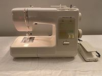 Side view of Kenmore 20 sewing machine with foot pedal laying beside it on a cloth surface.