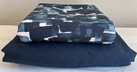 Two folded pieces of upholstery fabric stacked, top is patterned cotton, bottom is solid navy linen