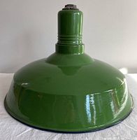 Overall view of the vintage barn light shade showing green enamel exterior and white interior, with slight reflections on the surface.