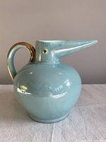 Side view of aqua iridescent bird jug showing glossy surface and gold handle