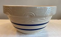 Side view showing the blue stripes and embossed rainbow pattern on exterior of large stoneware mixing bowl.