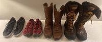 All four pairs of women's shoes and boots lined up: black Cole Haan shoes, burgundy Keen sandals, brown Fiorentini & Baker boots, and dark brown Ugg boots.