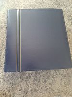 Blue hardcover binder album with gold stripe on spine and front cover.