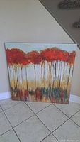Frontal view of large square canvas art featuring textured tree tops painted in warm colors.