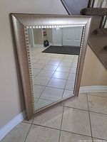 Mirror positioned vertically against wall showing clear reflection and part of staircase in background.