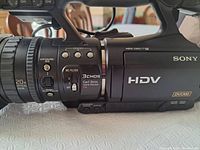 Left side of camcorder showing lens assembly with Carl Zeiss branding, ND filter and exposure iris controls