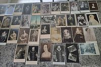 Overhead view of about 35 vintage British monarchy postcards arranged on a flat surface showing portraits of kings, queens, and related historic images.