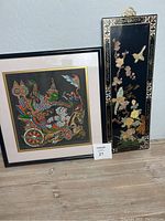 Photo showing Prince Ramakien silk painting and Asian mother of pearl wall hanging together on the floor against a wall.