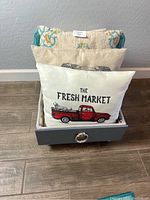 Throw pillows arranged inside handmade painted drawer blanket box showing truck design pillow front