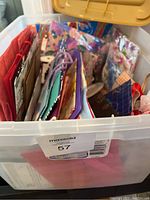 Plastic tub filled with an assortment of colorful gift bags and wrapping materials visible from above.