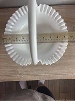 White milk glass basket with scalloped edge and handle, shown with a ruler measuring width approximately 10 inches
