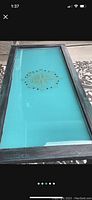 Top view of repurposed glass double pane window coffee table showing compass design on turquoise background glass