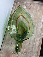 Green glass swan showing leaf-shaped body and swan head with neck, layered green and brown tones.