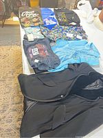 Photo of all clothing items laid out on table showing vintage tuxedo jacket with velvet lapels and variety of new men's clothing items with tags