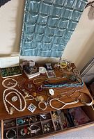 Table with assorted vintage jewelry including necklaces, earrings, bracelets and perfumes