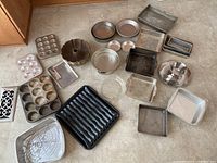 Full assortment of metal bakeware including cake pans, muffin tins, Bundt pan, loaf pans, roasting pan, cooling rack, and baking sheets.