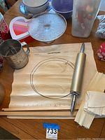Table with vintage fabric pastry cloth, metal rolling pin, and other baking items arranged.