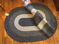 Two oval braided rugs stacked, showing braided texture and predominant blue colors.