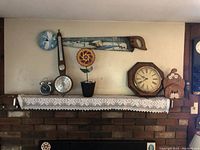 Wide view of shelf displaying two clocks, decorative saw, barometer, and assorted small items.
