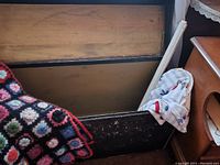 Inside inside view of antique wooden trunk showing wooden interior and three throws inside.