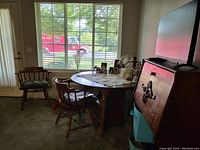 Maple drop leaf kitchen table with four chairs around it, two of which have arms, in a living space near window.