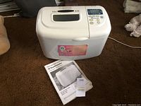 Photo of ToastMaster bread maker alongside instruction manual and auction lot tag