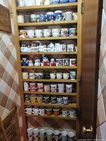 Photo of multiple shelves filled with assorted coffee mugs and some creamers, sugar bowls, and salt and pepper shakers.
