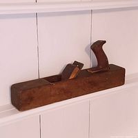 Photo of antique wooden hand planer showing the wooden body, handle, and blade opening.