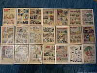 22 vintage comic book pages arranged in rows on a blue surface, showing colorful illustrated story panels with various cartoon and comic strip characters from mid-20th century.