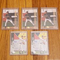 Front view of 3 Classic Best Gold #83 Derek Jeter cards and 2 Upper Deck Minor League #185 cards placed on wooden surface.