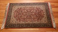 Full view of rectangular oriental rug on wooden floor showing fringed ends.