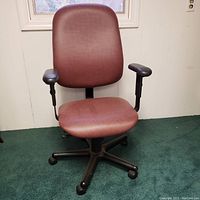 Front view of a burgundy fabric rolling office chair with black armrests and five caster wheels.