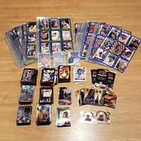 Flat lay of approximately 600 NASCAR racing cards sorted and unsorted, some in protective sleeves, some loose, laid out on a wooden floor with visible cards featuring Dale Earnhardt Sr. and other drivers.
